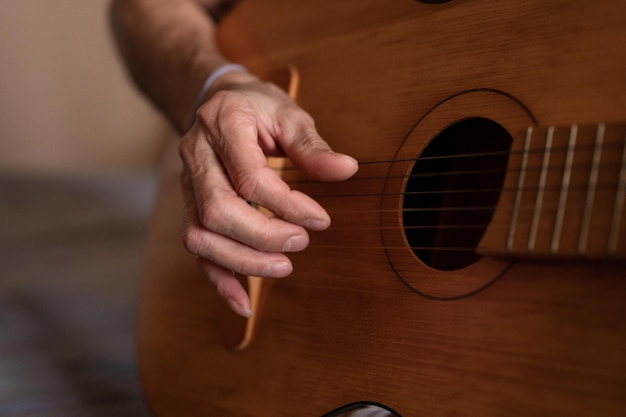 Mãos masculinas de um homem caucasiano sênior idoso segurando e tocando um violão clássico fecham em casa guitarrista sem rosto não profissional as pessoas tocam música amadora hobbies domésticos e lazer