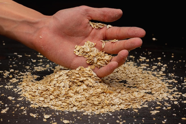 Mãos masculinas derramando muesli em um fundo preto