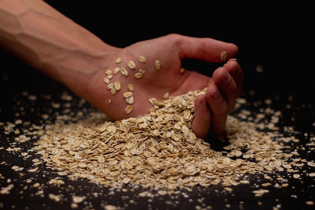 Mãos masculinas derramando muesli em um fundo preto