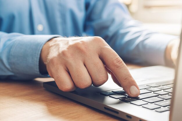 Mãos masculinas digitando em um teclado de laptop, vista de perto