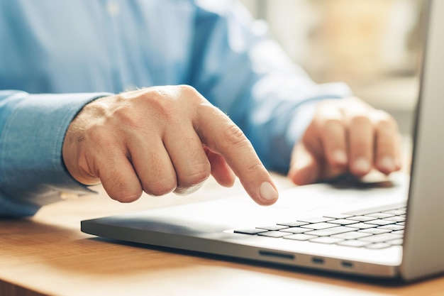 Mãos masculinas digitando em um teclado de laptop, vista de perto