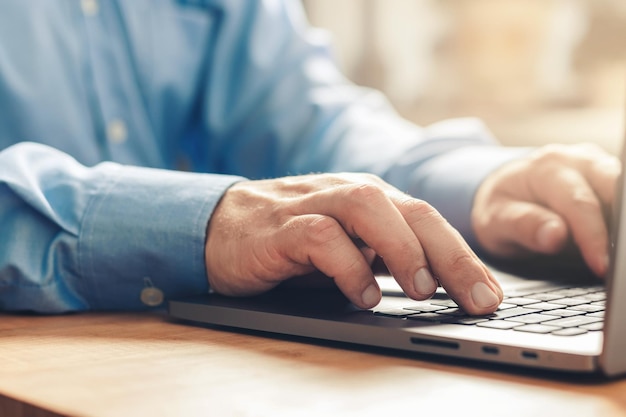 Mãos masculinas digitando em um teclado de laptop, vista de perto