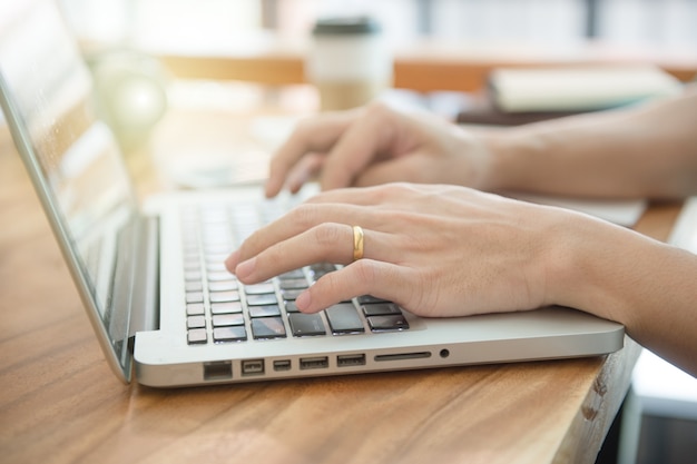 Foto mãos masculinas do negócio que datilografam em um teclado do portátil na mesa com uma xícara de café na noite.