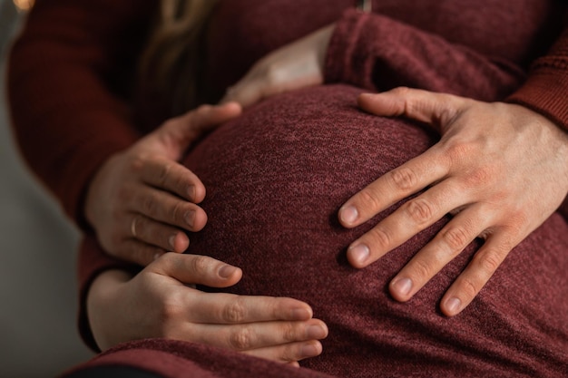 Foto mãos masculinas e femininas abraçam a barriga grávida da menina esperando um pequeno milagre