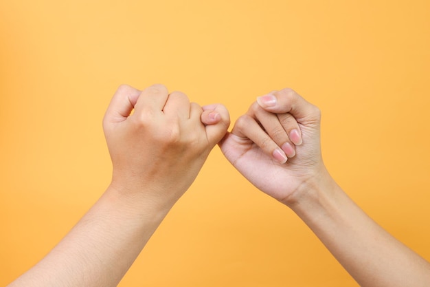 Mãos masculinas e femininas se agarram um ao outro o dedo mindinho como um símbolo de promessa ou perdão isolado