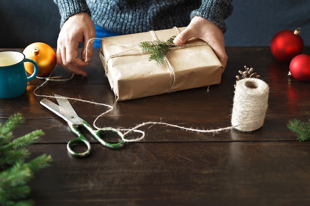 Mãos masculinas embrulho mesa de madeira de presente de natal