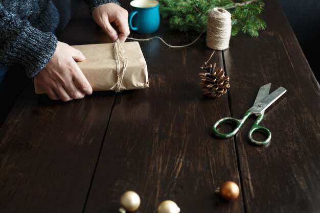 Mãos masculinas embrulho mesa de madeira de presente de natal