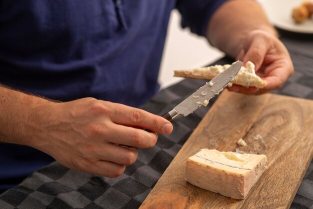 mãos masculinas espalhando queijo macio na torrada