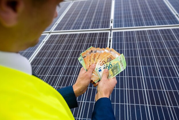 Mãos masculinas fortes de um trabalhador segurando notas de euro pelo trabalho feito O conceito de pagamento pela instalação de painéis solares