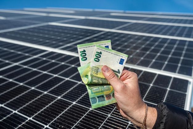 Mãos masculinas fortes de um trabalhador segurando notas de euro pelo trabalho realizado O conceito de pagamento pela instalação de painéis solares eletricidade verde
