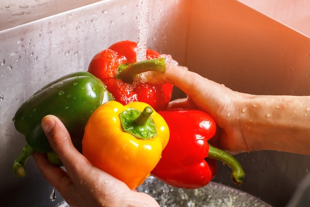 Mãos masculinas lavando o pimentão. Pimentão amarelo e verde. Saúde e saciedade. Melhor ingrediente para salada doce.