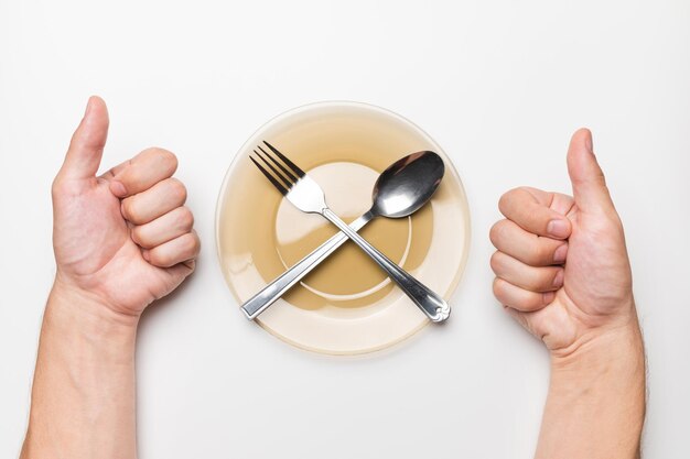 Foto mãos masculinas mostram um gesto de classe uma mesa branca um prato vazio e um garfo e uma colher deitam-se sobre ele