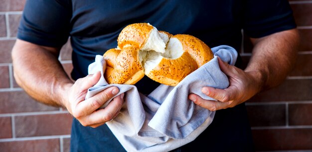 Mãos masculinas que quebram o pão recentemente cozido, close up.