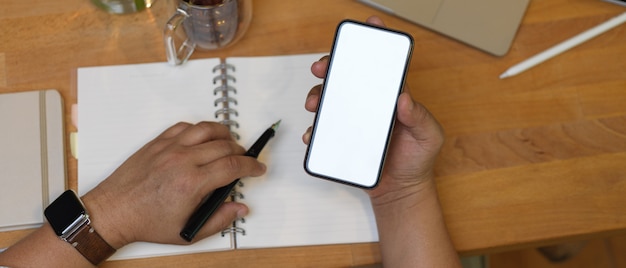 Mãos masculinas segurando um smartphone com tela branca