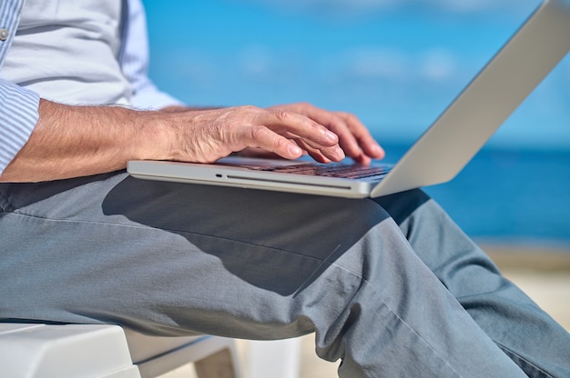 Mãos masculinas trabalhando em um laptop ao ar livre