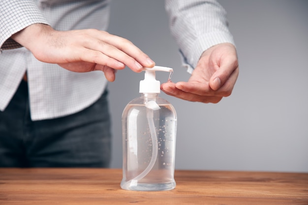Mãos masculinas usando álcool gel para lavar as mãos ou dispensador de frascos de desinfetante, contra o novo coronavírus