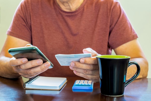 Mãos masculinas usando aplicativos de calculadora na mesa