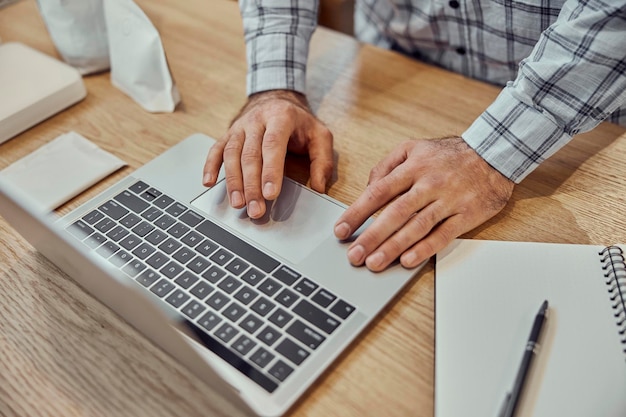 Mãos masculinas usando laptop moderno na mesa de madeira