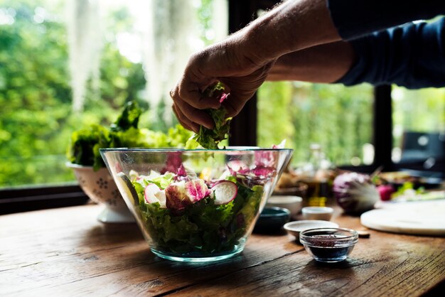 Mãos, misturando, salada, em, um, tigela vidro