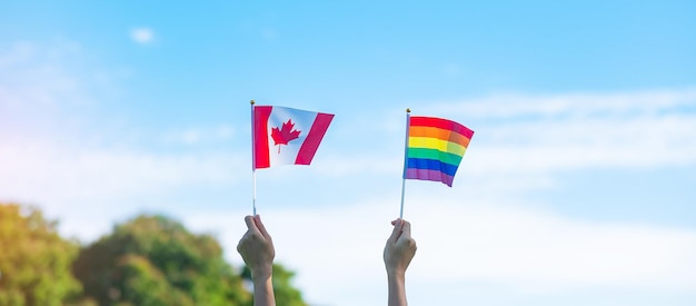 Mãos mostrando a bandeira LGBTQ Rainbow e Canadá no fundo da natureza Apoie a comunidade Lésbica Gay Bissexual Transgênero e Queer e o conceito do mês do orgulho