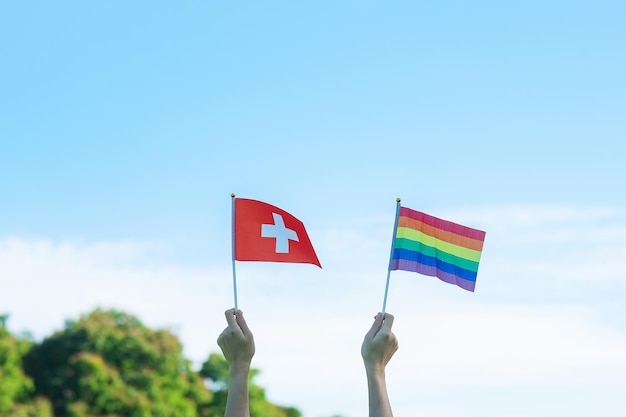 Mãos mostrando a bandeira LGBTQ Rainbow e Suíça no fundo da natureza Apoie a comunidade Lésbica Gay Bissexual Transgênero e Queer e o conceito do mês do orgulho
