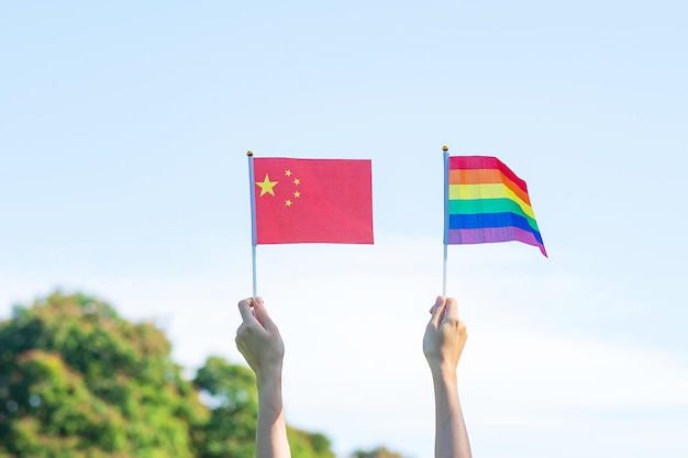 Mãos mostrando lgbtq rainbow e bandeira da china no fundo da natureza apoie a comunidade lésbica gay bissexual transgênero e queer e o conceito do mês do orgulho