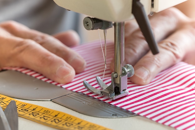 Mãos na máquina de costura segurando um tecido