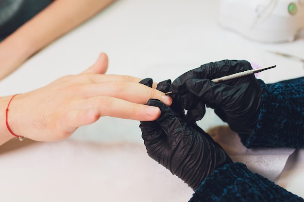 Mãos nas luvas se preocupa com as unhas do homem. Manicure salão de beleza.