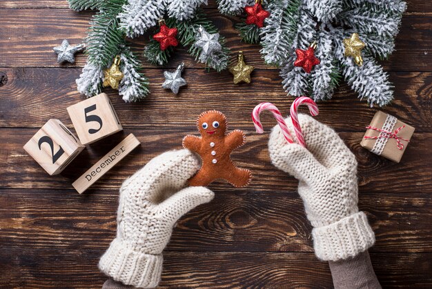 Mãos nas luvas segurando homens de gengibre. 25 dezembro