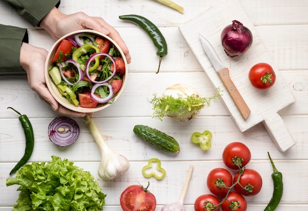 Mãos organizando uma tigela com salada