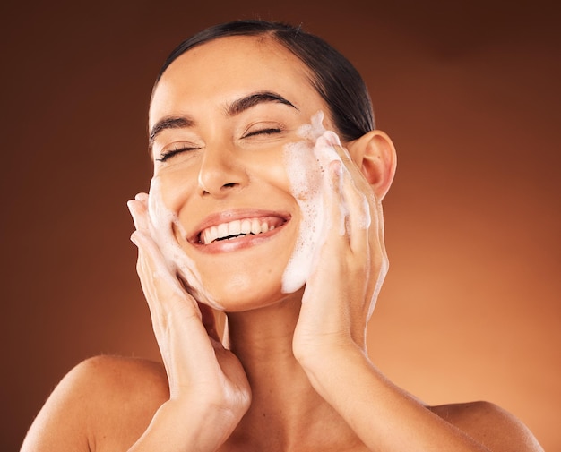 Foto mãos para cuidados com a pele e espuma no rosto para limpeza com sorriso, felicidade e bem-estar no spa lavagem facial, terapia cosmética de luxo e autocuidado com sabonete para cuidados com a beleza, dermatologia e cosmetologia