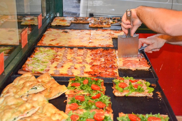 mãos quebrando pedaços quadrados de pizza