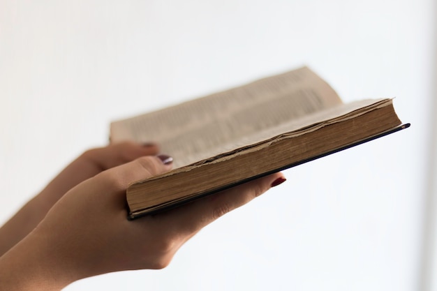 Foto mãos segurando a bíblia sagrada aberta e orando.