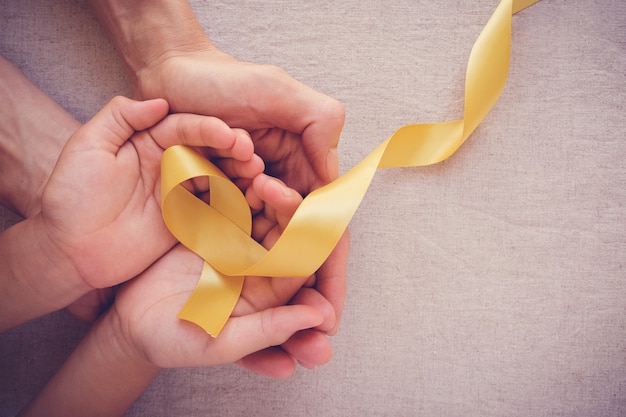 Foto mãos segurando a fita de ouro amarelo, sarcoma awareness