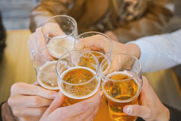 Mãos segurando copos de cerveja e torcendo