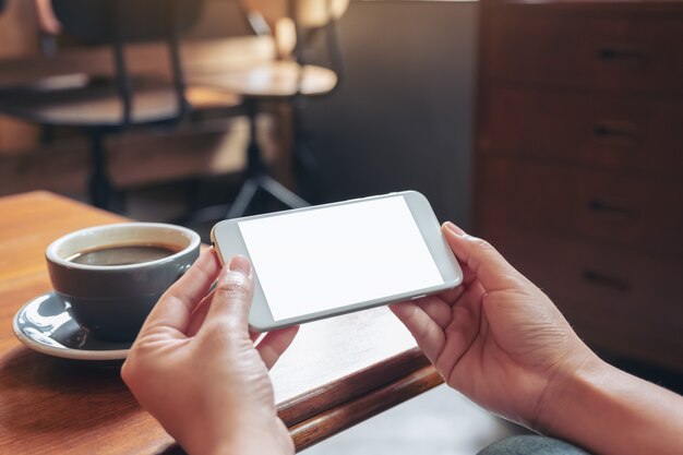 mãos segurando e usando um telefone celular branco com tela em branco