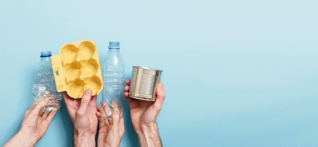 Mãos segurando lixo reciclado contra um fundo azul