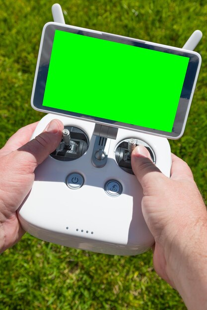 Foto mãos segurando o controlador de quadrocóptero de drone com tela verde em branco