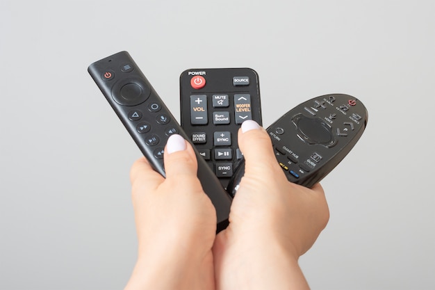 Mãos segurando os controles remotos de tv