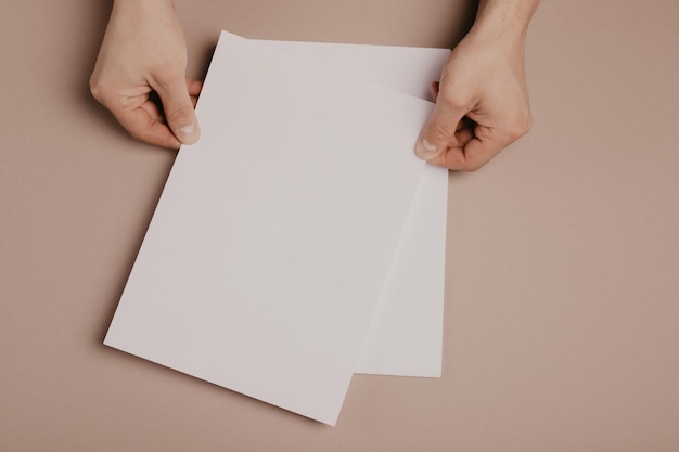 Mãos segurando papel em branco tamanho a4 em fundo cinzento