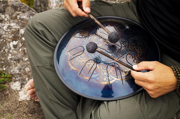 Foto mãos segurando pauzinhos de tambor e tocando instrumento de percussão de tambor de língua de aço de mão moderna