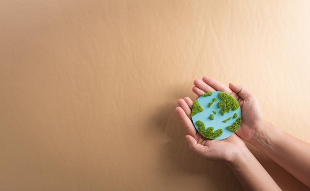 Mãos segurando terra de papel com grama em fundo marrom Dia mundial do meio ambiente dia da terra e salvar o conceito de terra