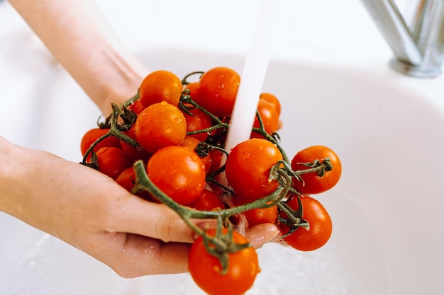 Mãos segurando tomates cereja sob água corrente