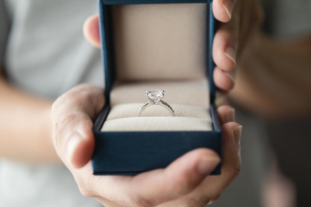 Mãos segurando um anel de diamante em uma caixa de joias