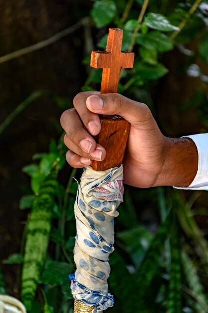 Mãos segurando um bastão com um crucifixo de madeira no folclore e em uma festa religiosa popular no Brasil