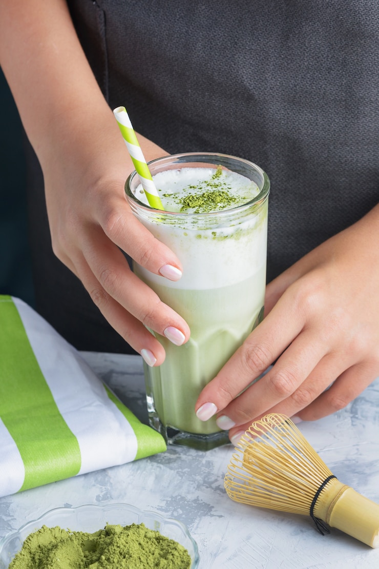 Foto mãos segurando um café com leite feito de chá verde em um copo