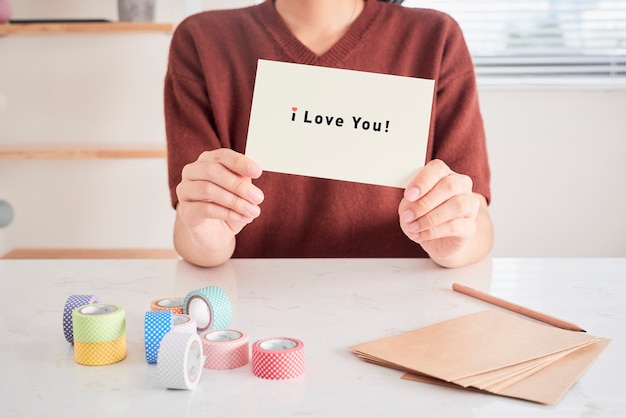 Mãos segurando um cartão com as letras de frase "eu te amo", preparadas para o amor