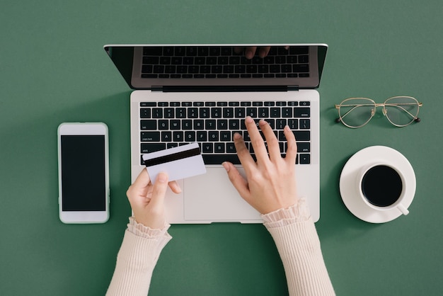 Mãos segurando um cartão de crédito de plástico e usando o laptop. Conceito de compras online