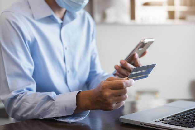 Foto mãos segurando um cartão de crédito e usando laptop no escritório em casa compras online