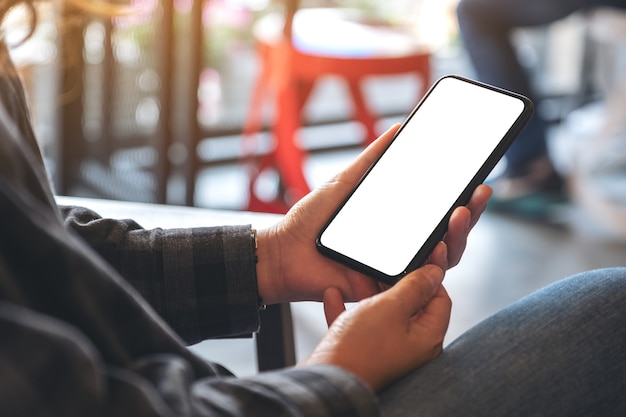 mãos segurando um celular preto com uma tela em branco em um café